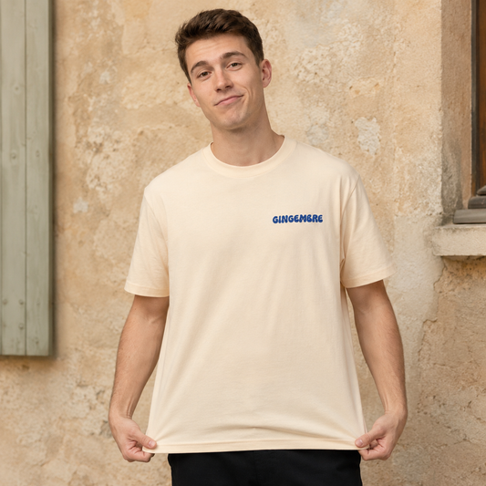 T-shirt Gingembre abricot porté de face devant un mur provençal, logo bleu imprimé sur la poitrine